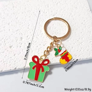 Close-up of golden metal Christmas keychain with green gift box and red stocking charms