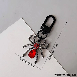 Porte-clés araignée gothique avec strass rouges et mesures sur fond gris épuré