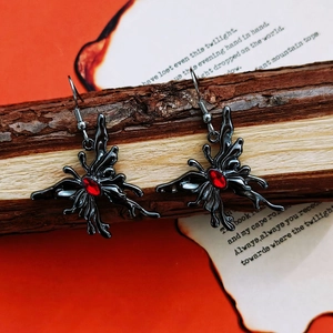 Gothic butterfly drop earrings with red oval gemstone on rustic wood background