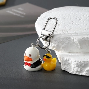 Close-up of resin cartoon duck keychain set with silver metal clasp on dark background