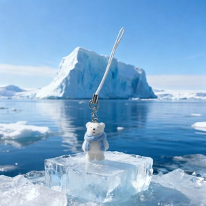 Detail of white flocked polar bear pendant with blue scarf on ice block background