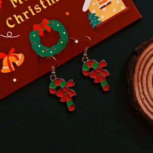 Detail of Christmas candy cane earrings with red bow and colorful enamel finish