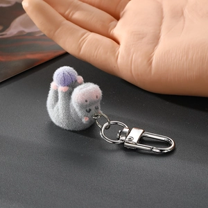Détail d'un porte-clés hippopotame floqué gris tenu à la main pour l'échelle de taille