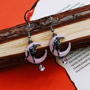 Macro detail of gothic pink moon earrings with black rose relief and drop crystal