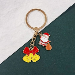 Detailed view of Santa Claus and golden bells pendants on a festive enamel keychain charm