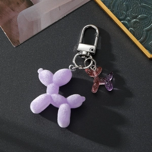 Close-up of a purple flocked balloon dog keychain with a pink glittery mini charm