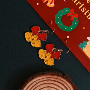 Detailed close-up of Christmas bell earrings with red bows on a festive background