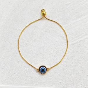 Bracelet ajustable œil porte-bonheur doré avec pendentif en émail bleu sur fond blanc