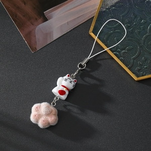 Detail of cute lucky cat keychain with pink flocking paw on a dark textured background