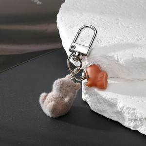 Detailed macro view of flocked Capybara pendant and resin animal charm with silver carabiner