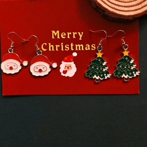 Christmas earrings set featuring Santa Claus and Christmas tree designs on a red festive card