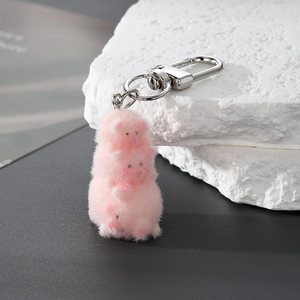 Detail of three stacked pink flocked pig charms with a silver metal keychain clasp