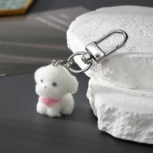 Porte-clés chiot blanc floqué avec écharpe rose et clip argenté sur pierre minimaliste
