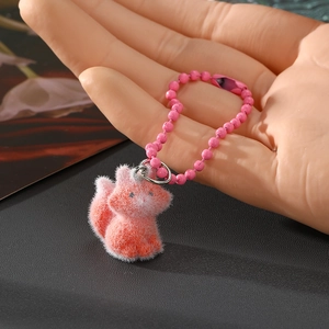Makro-Detail eines kleinen orange-rosa beflockten Katzen-Schlüsselanhängers in der Hand