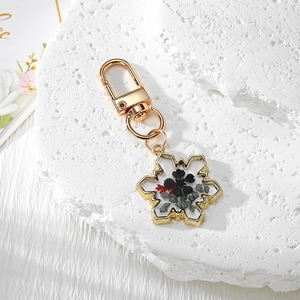 Gold snowflake keychain with black dried flowers in clear resin pendant