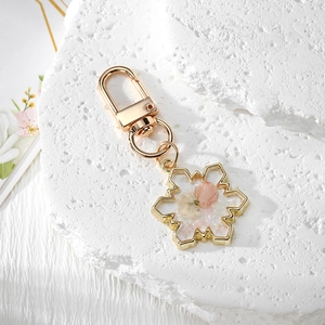Handmade snowflake resin keychain with pink dried flowers and golden metal frame