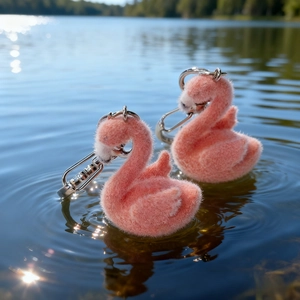 Cute pink flocked flamingo keychains with silver metal rings on a lake background