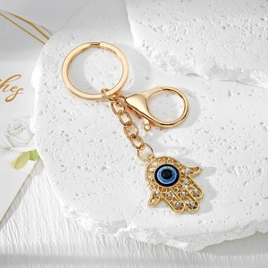 Macro detail of golden Hamsa Hand keychain with blue evil eye and sparkling crystals