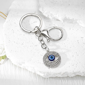 Macro view of blue Evil Eye keychain with sparkling rhinestones on textured stone surface