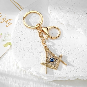 Close-up of Freemason compass and square keychain with blue evil eye and sparkling crystals
