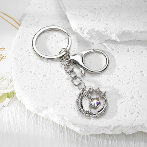 Detailed close-up of silver hollow moon wreath keychain with aurora gemstone on stone