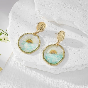Irregular gold earrings with real white daisy flowers and blue resin stones on white stone
