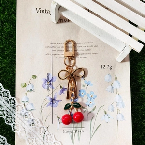 Detailed view of sweet cherry keychain with golden bow and red fruit on vintage background