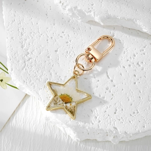 Star-shaped golden keychain with real white daisy dried flower in transparent resin