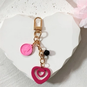 Detail of pink coin pendant with Elizabeth II relief and golden double heart keychain charm