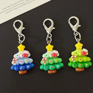 Three colorful resin Christmas tree keychains with stars and hooks on black background