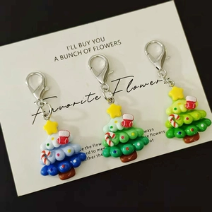 Three colorful Christmas tree keychains with Santa theme and silver metal hooks on a card