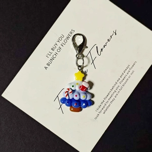 Close-up of a blue and white resin Christmas tree keychain with red sock and yellow star