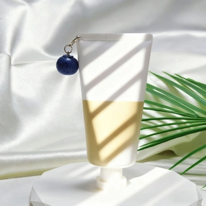 Detailaufnahme einer zweifarbigen Kosmetiktube mit marineblauem mattem Kugelornament