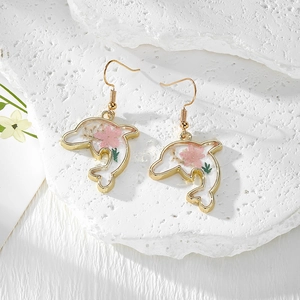 Vue détaillée des boucles d'oreilles dauphin en résine avec vraies fleurs séchées et crochets dorés