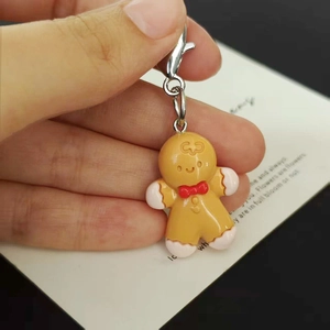 Close-up of handmade gingerbread man charm with white cream texture and silver lobster clasp