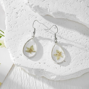 Gros plan de boucles d'oreilles artisanales en résine avec de vraies fleurs séchées jaunes