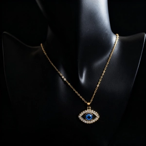 Golden Evil Eye necklace with blue bead and sparkling rhinestones on black display