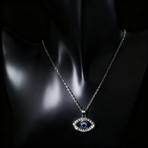 Detailed close-up of a silver Evil Eye pendant with blue stone on a black mannequin