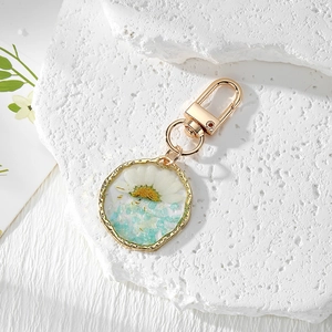 Irregular resin keychain with white daisies and mint green stones on textured block