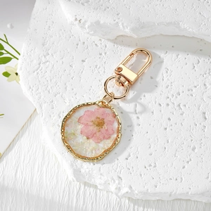 Handmade gold pendant keychain with pink dried flowers in irregular resin frame