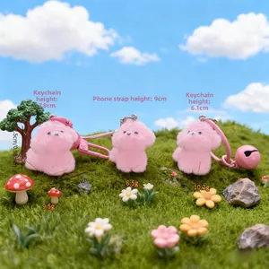 Detailed view of pink plush puppy charms with bells and keychains on a grass landscape