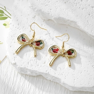 Detailed close-up of handmade gold bow earrings with real red dried flowers in resin