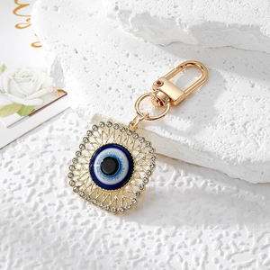 Detailed close-up of a gold Evil Eye charm with sparkling rhinestones and lobster clasp