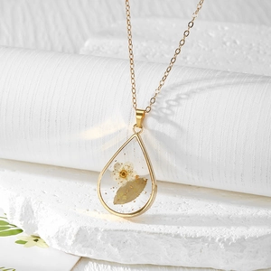 Elegant gold teardrop resin necklace featuring real dried flowers on white display