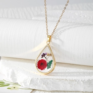 Detail of teardrop resin pendant with real red dried flowers and golden chain