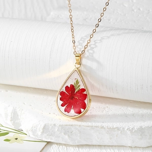 Detail view of water drop resin pendant with real red dried flowers and gold foil