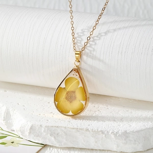 Close-up of a drop-shaped resin pendant with a yellow flower and gold metal frame