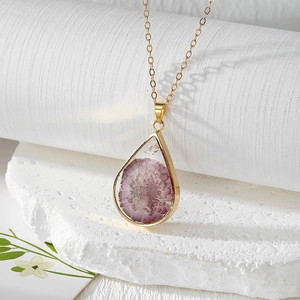 Detailed view of teardrop resin pendant with real pink dried flowers on stone base
