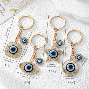 Detail of four gold Evil Eye keychains with blue star and geometric patterns with rhinestones