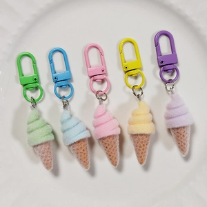 Set of five colorful flocked ice cream cone keychains in a white ceramic dish